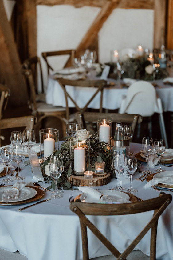 Ein festlich gedeckter Tisch mit weißen Kerzen und Blumen in warmem Kerzenlicht