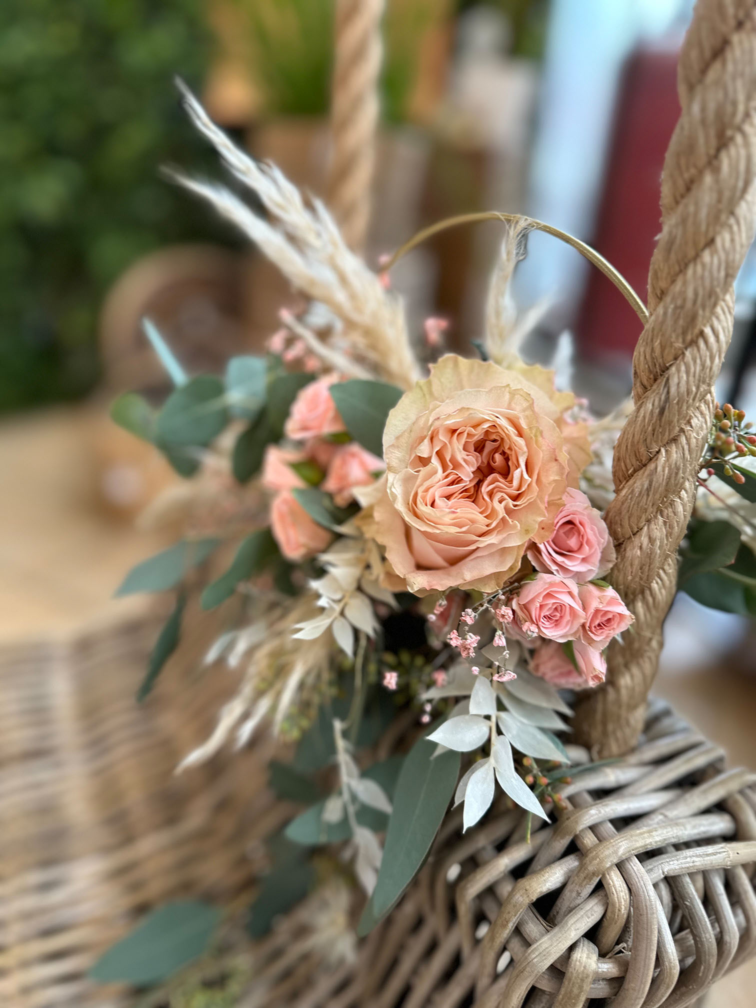 Ein schöner Strauß aus altrosa Rosen und Eukalyptus schmückt eine geflochtene Schaukel